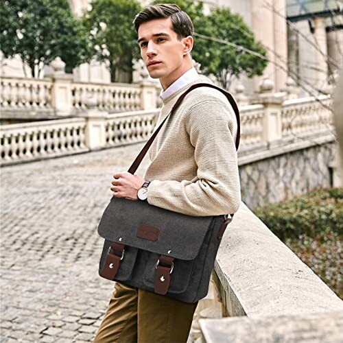 Man with a messenger bag standing near a stone railing.