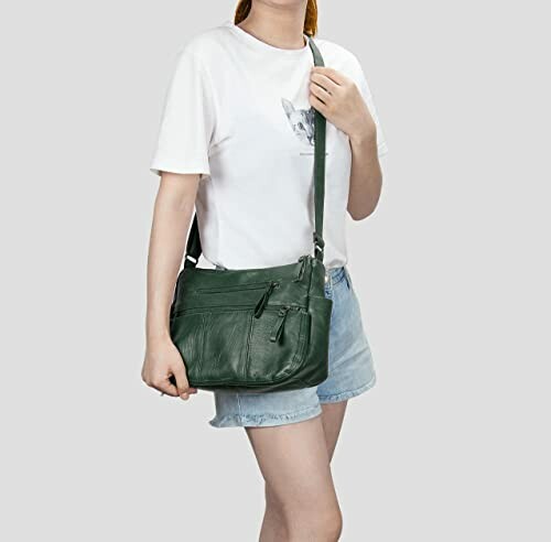 Woman with green leather crossbody bag wearing white t-shirt and denim shorts.