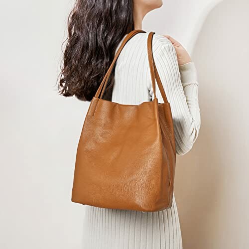 Woman wearing a white sweater with a brown leather tote bag